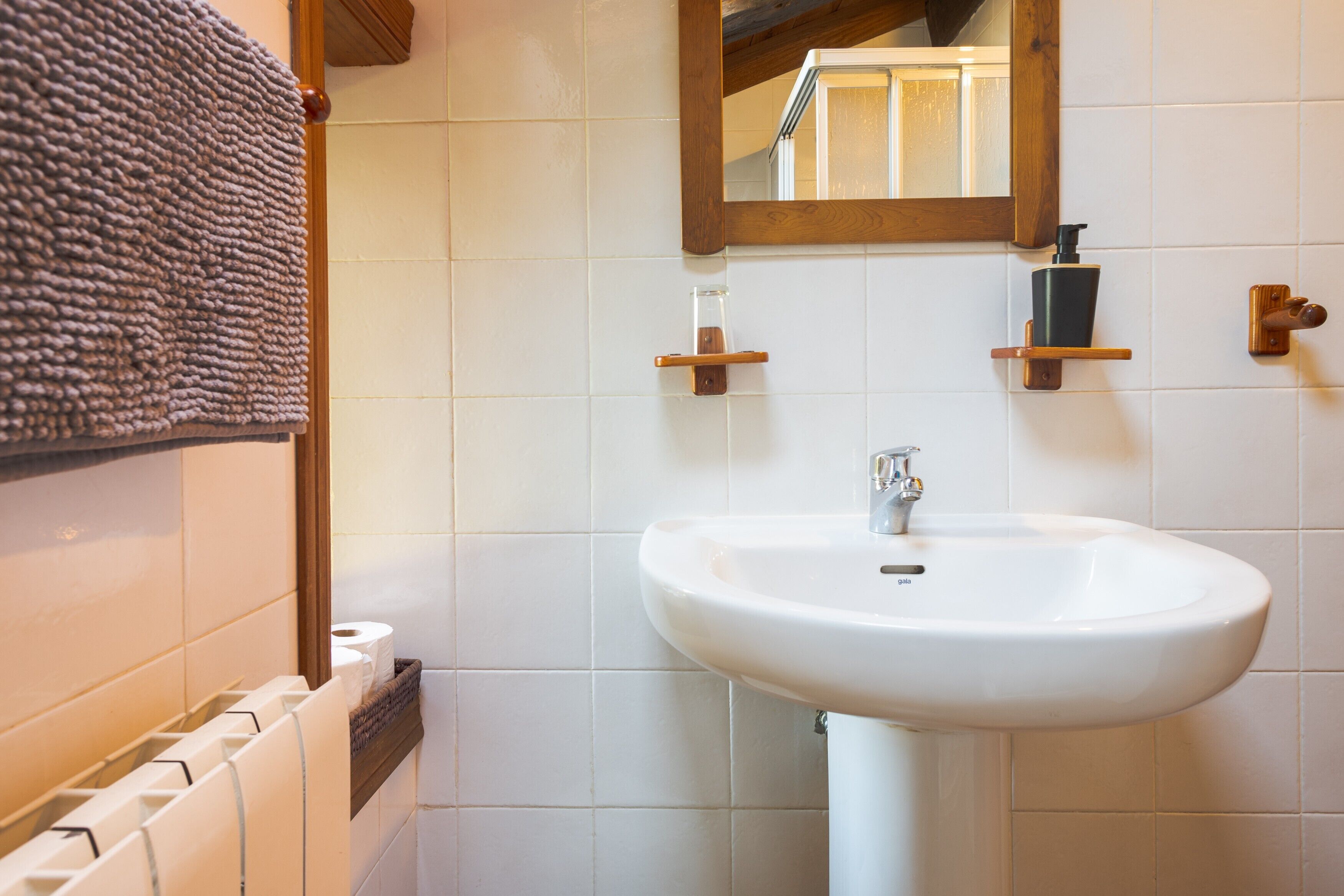 Ein Badezimmer mit einem weißen Waschbecken, einem Spiegel und einem Handtuch an der Wand.