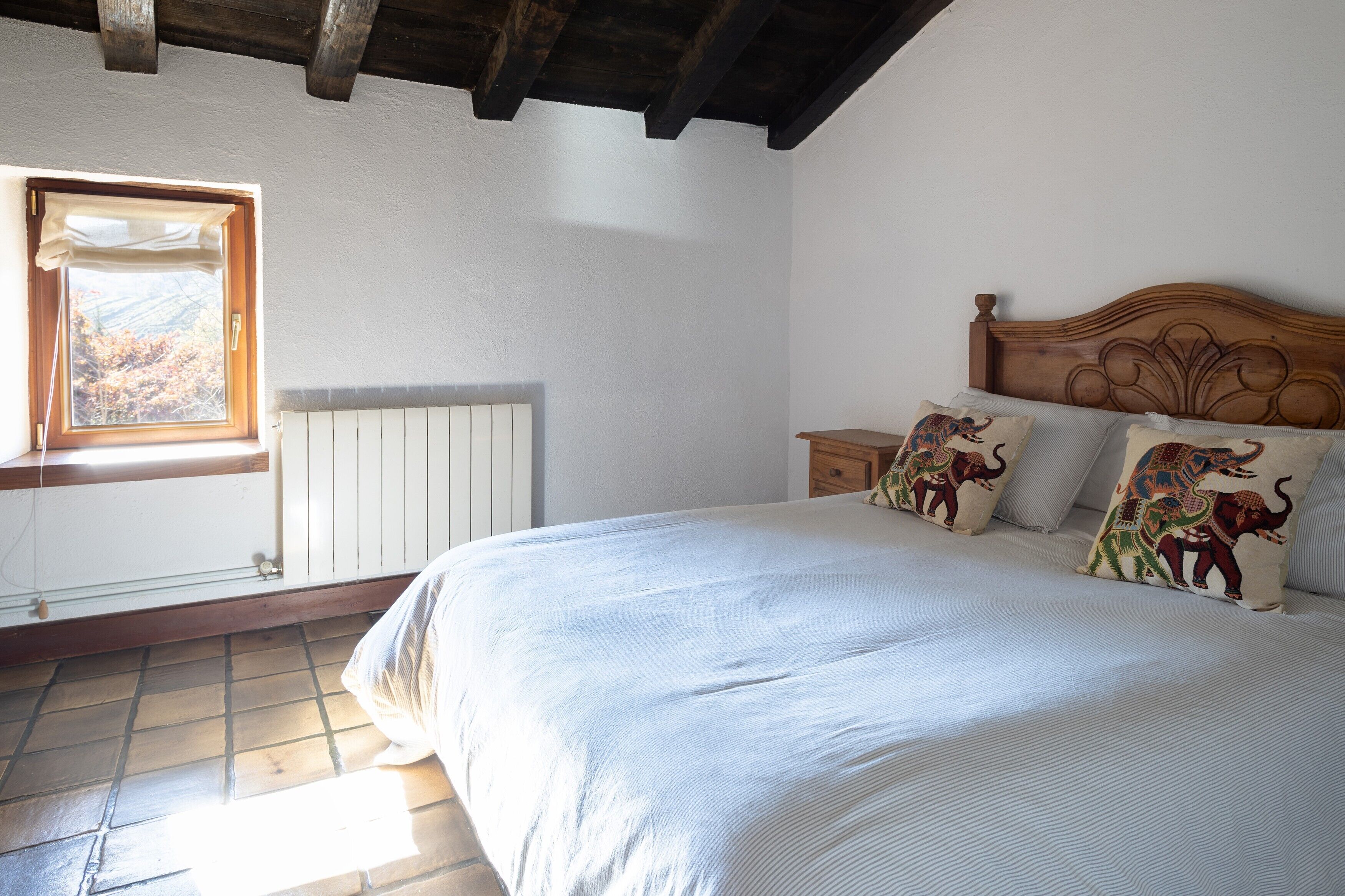 Ein Schlafzimmer mit Bett, Fenster, Heizkörper und Holzboden.