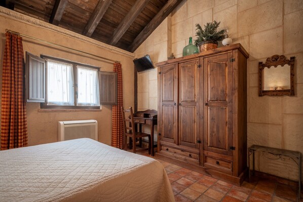 Un dormitorio con cama, armario de madera, escritorio y radiador.