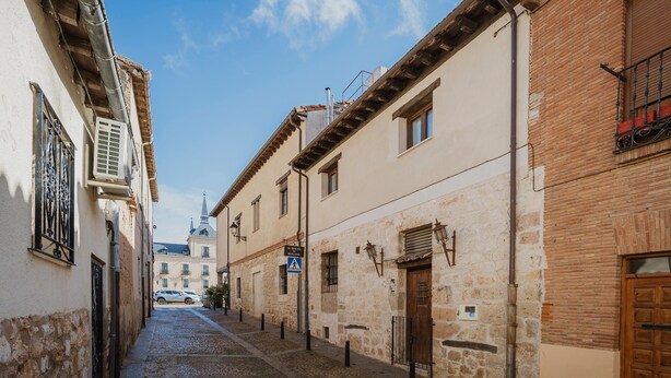 A narrow cobblestone street flanked by buildings with stone facades, a church spire in the distance, and a clear blue sky. - Country House 'El Desvan Del Brigante' with Balcony, Wi-Fi and Air Conditioning (Lerma)