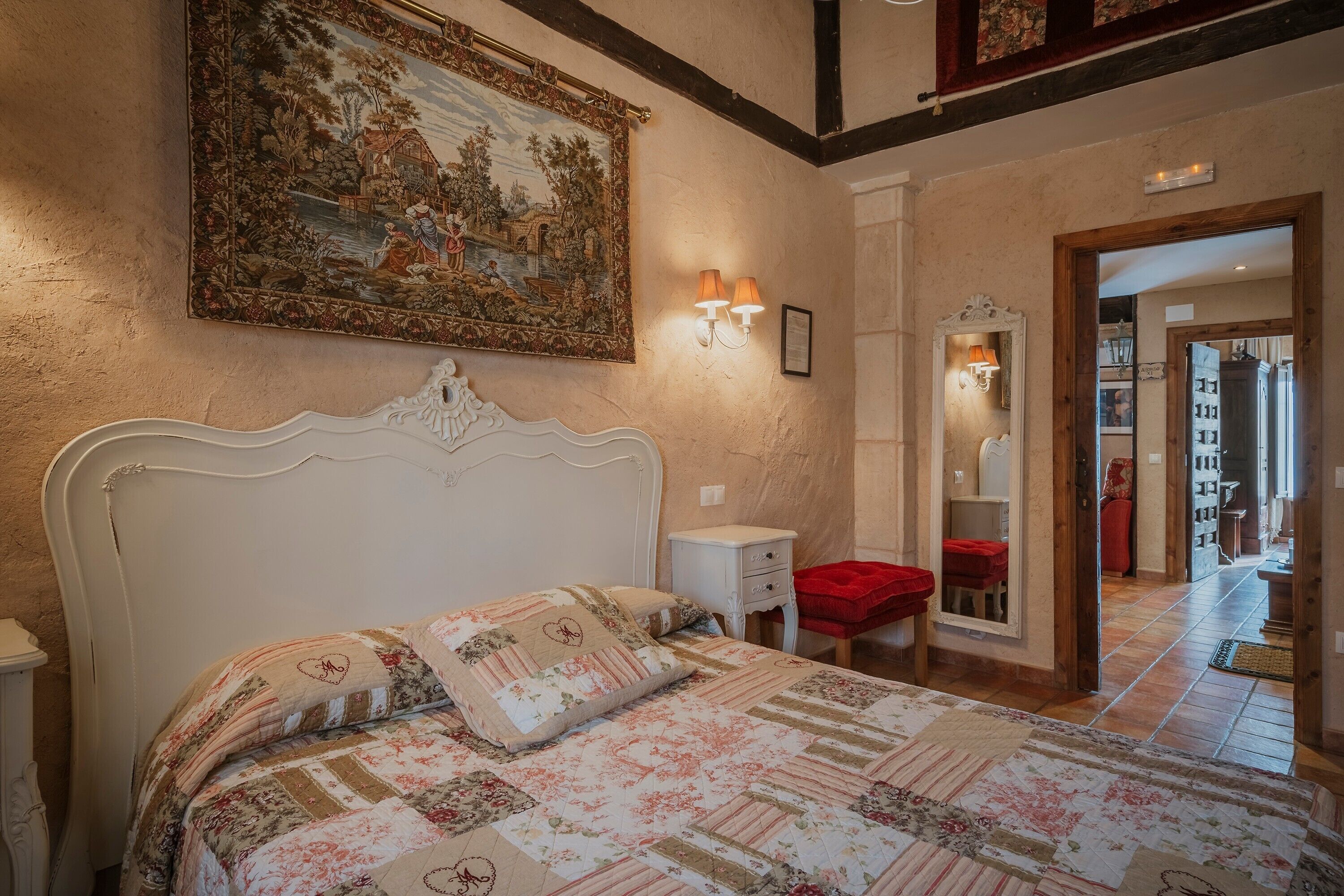 Un dormitorio con una cama grande, una mesita de noche, un aparador, un espejo y un cuadro en la pared.