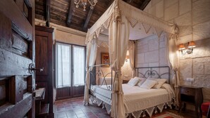 A traditional room with a four-poster bed, a wooden door, a stone wall, and a red patterned rug. - Country House 'El Desvan Del Brigante' with Balcony, Wi-Fi and Air Conditioning (Lerma)