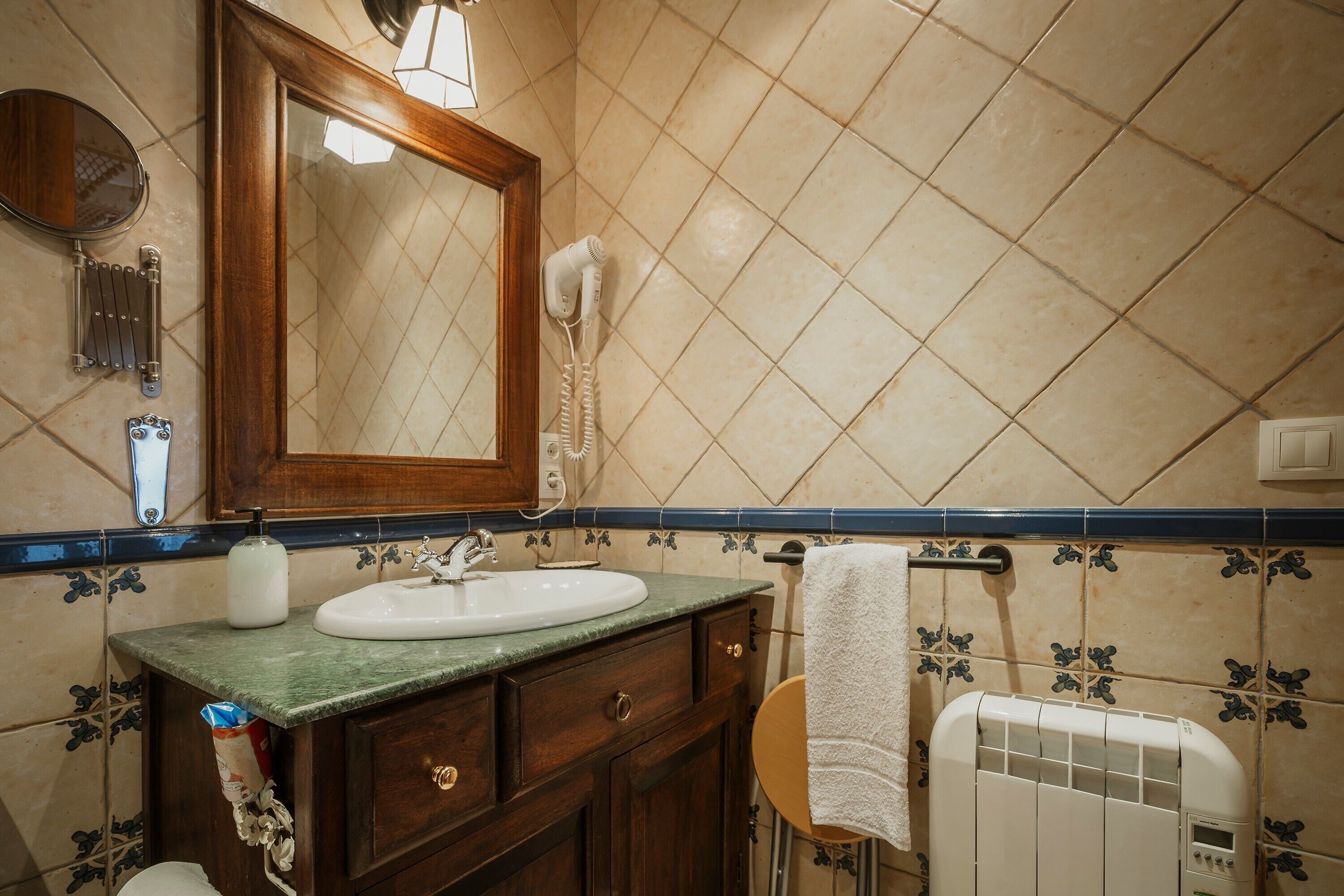 Une salle de bain avec un meuble-lavabo en bois, un miroir, un lavabo, un porte-serviettes et un radiateur.