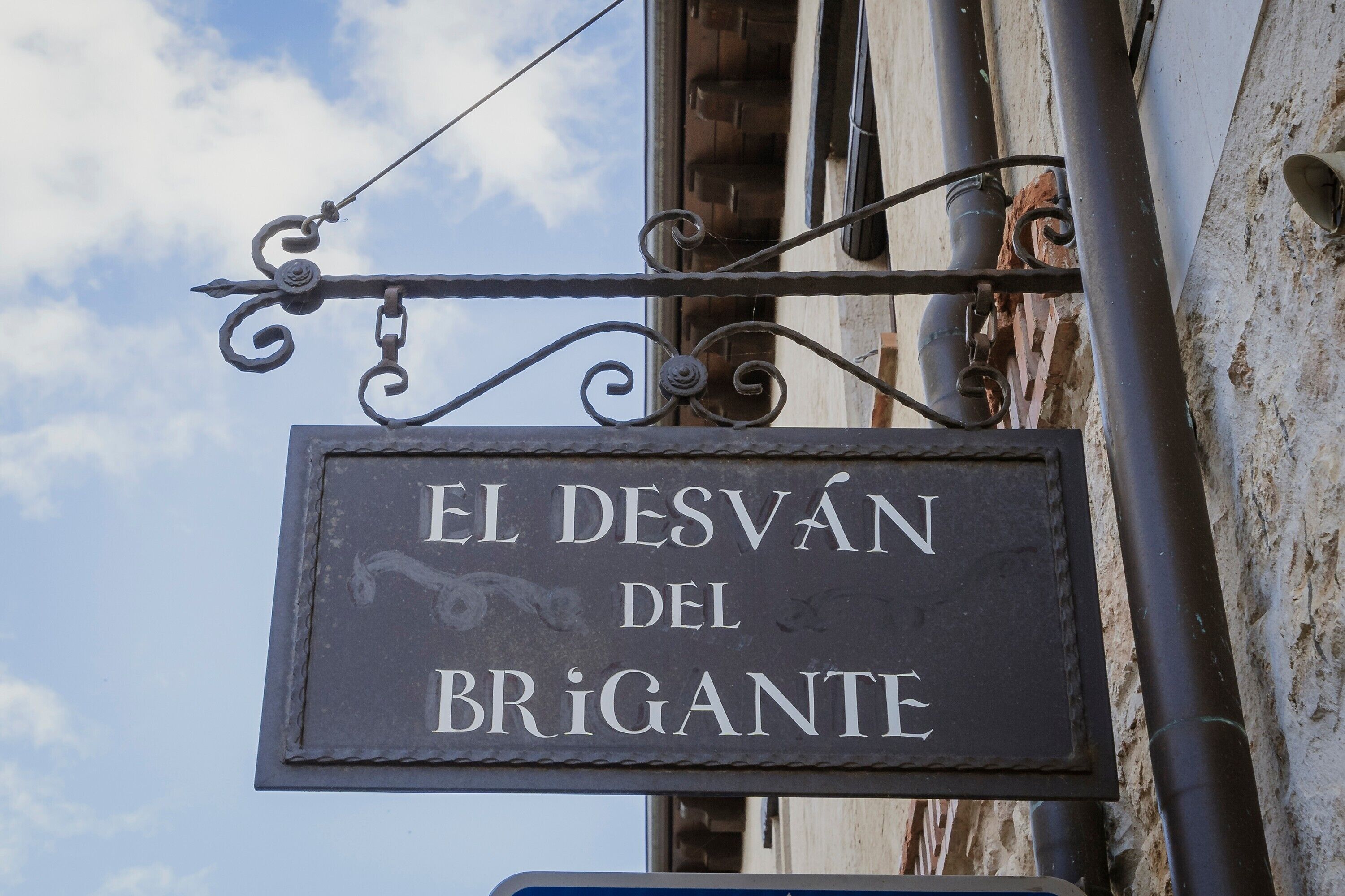 Une enseigne portant l’inscription « EL DESVÁN DEL BRIGANTE », fixée sur une structure métallique.