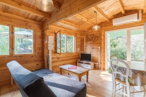 Eine Holzhütte mit Sofa, Tisch, Fernseher und einer Fahrraddekoration.