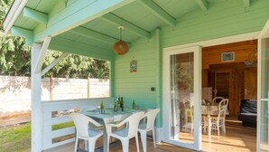 A covered patio with a table and chairs, a wooden deck, and a view of the backyard. - Holiday Home 'Le Colibri' with Private Pool, Wi-Fi and Air Conditioning (La Ciotat)