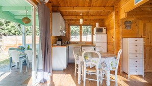 A wooden cabin with a kitchen, dining area, and a covered patio. - Holiday Home 'Le Colibri' with Private Pool, Wi-Fi and Air Conditioning (La Ciotat)