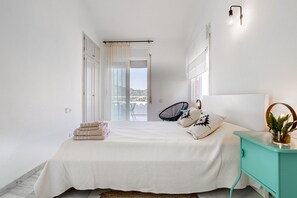 A bedroom with a bed, a nightstand, a chair, and a view of the outside. - Holiday Home 'Torre Mirador Azul 2 Habitaciones' with Sea View, Private Pool and Wi-Fi (Tossa de Mar)