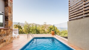 Ein Pool mit Blick auf Hügel, ein wei ßer Stuhl und ein Blumentopf.
