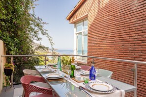 A dining table set on a balcony with a view of the sea, surrounded by brick walls and potted plants. - Holiday Home 'Torre Mirador Azul 2 Habitaciones' with Sea View, Private Pool and Wi-Fi (Tossa de Mar)