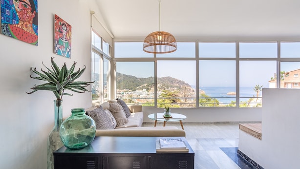Ein modernes Wohnzimmer mit einer Couch, einem Couchtisch und Blick auf das Meer.