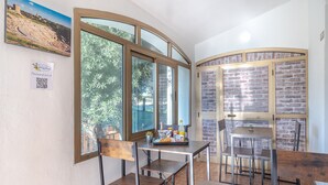 A dining area with a table, chairs, and a window with a view of trees. - Villa 'Leale Plemmirio' with Private Pool, Wi-Fi and Air Conditioning (Siracusa)