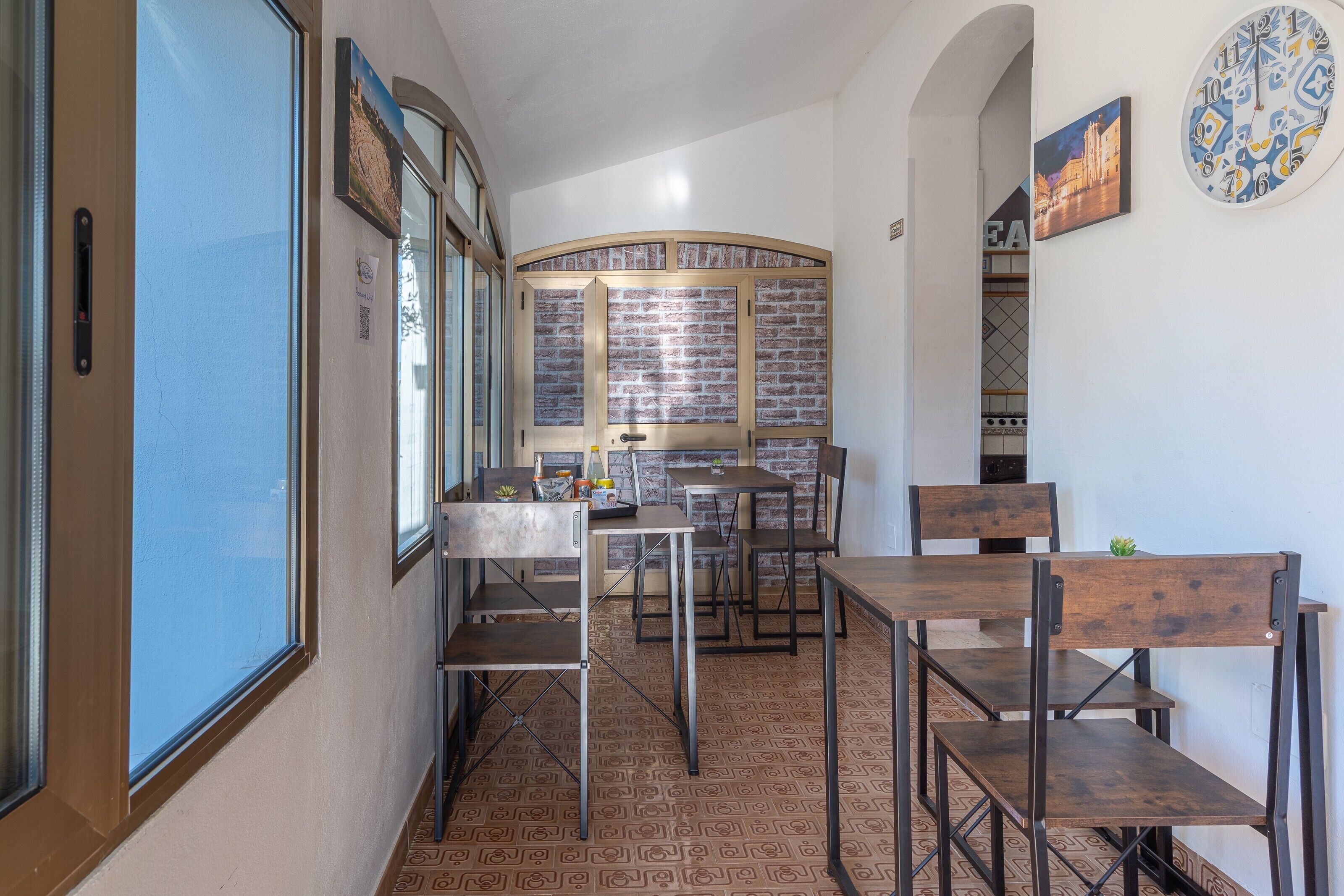 Un comedor con mesas y sillas, un muro de ladrillo y un reloj en la pared.