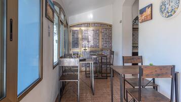 Un comedor con mesas y sillas, un muro de ladrillo y un reloj en la pared.