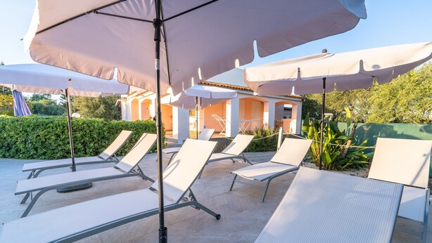 Outdoor lounge chairs with umbrellas, a tiled patio, and a building in the background. - Villa 'Leale Plemmirio' with Private Pool, Wi-Fi and Air Conditioning (Siracusa)