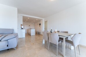 A modern interior with a dining area, a sofa, and a kitchen in the background. - Apartment 'Paraiso' with Sea View, Wi-Fi and Air Conditioning (Fuengirola)