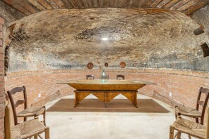 A room with a brick wall, a wooden table with chairs, and a tiled ceiling. - Country house 'Casa Estel Miracle' with private terrace and private inner patio (Juncosa)