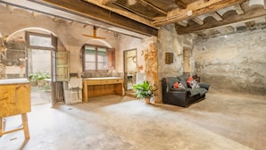 A rustic room with exposed beams, a wooden desk, a sofa, and a potted plant.