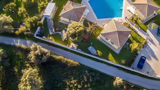 An aerial view of a residential area with a swimming pool, multiple houses, and surrounding greenery. - Holiday Home 'Dioni' with Mountain View, Wi-Fi and Air Conditioning (Lefkada)