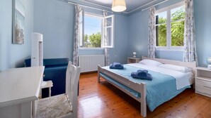 A bedroom with a bed, a chair, a desk, and a window with curtains.