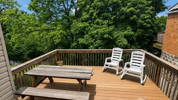 Eine Holzterrasse mit einem Picknicktisch und zwei weißen Liegestühlen.