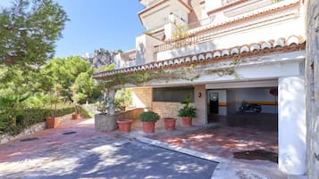 Un edificio con fachada de piedra, tejado de tejas y un balcón con plantas.