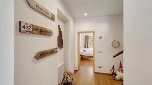 A hallway with wooden signs indicating room numbers and names, a bed in the background, and a gnome decoration on the right. - Room 1 - Nene Cristina with External Bathroom, Shared Terrace and Garden (Pieve di Cadore)