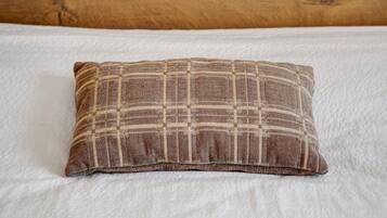 A pillow with a checkered pattern on a bed with white bedding.