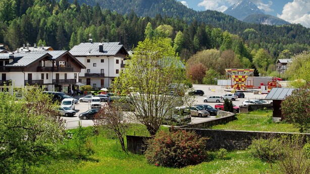 Un pueblo con edificios, un estacionamiento y una montaña al fondo.