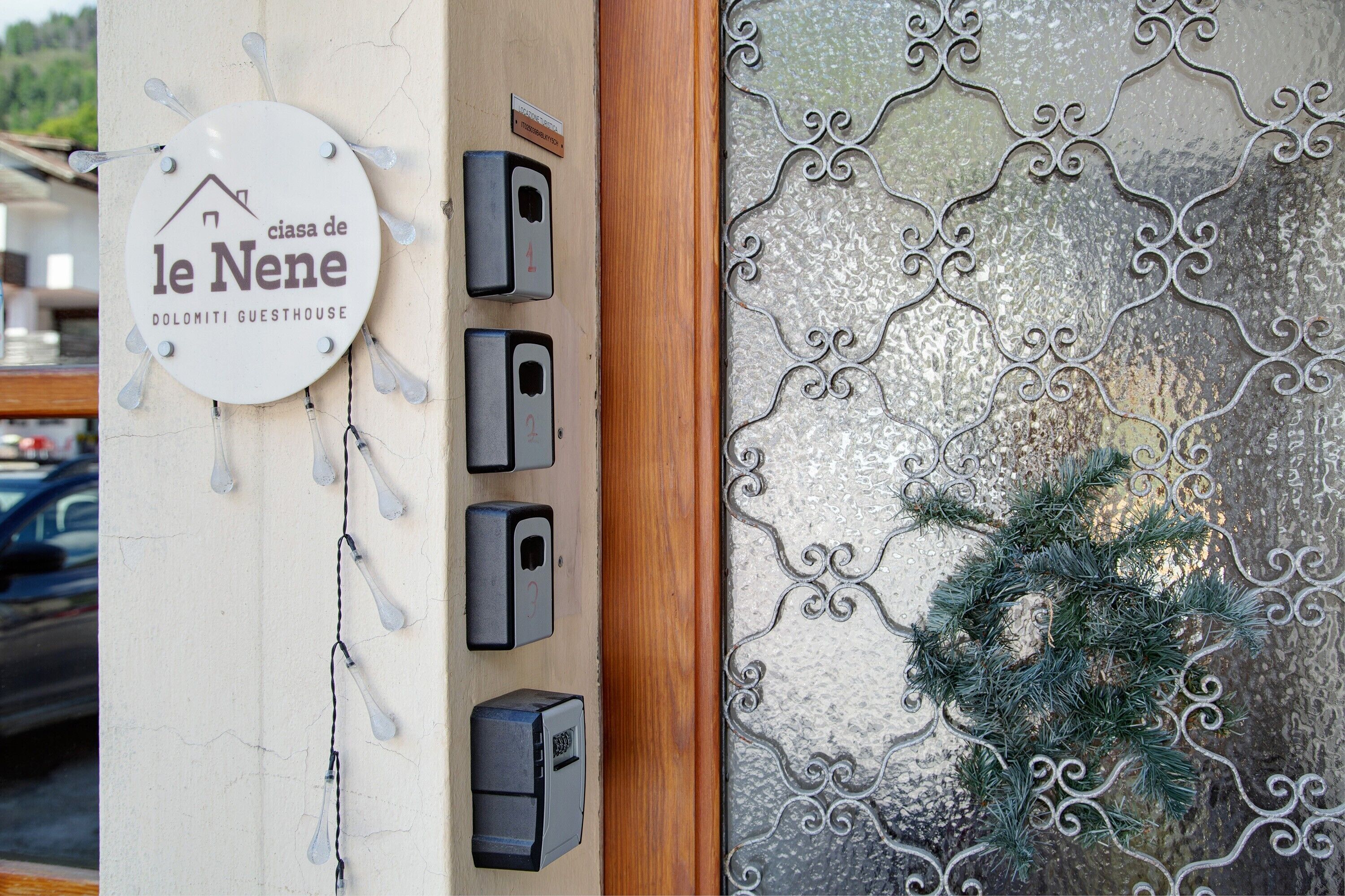 Une porte ornée d’un motif métallique décoratif et d’une enseigne indiquant « le Nene Dolomiti Guesthouse ».