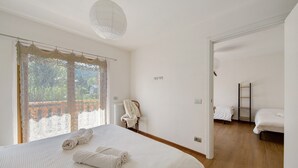A bedroom with a large bed, a radiator, a chair, and a view through a window. - Room 4 – Nene Maria with Terrace and Shared Garden (Pieve di Cadore)