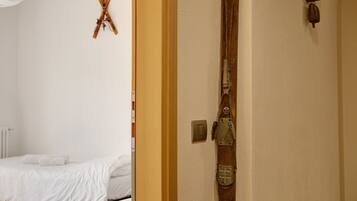 A room with a bed, a wooden door, and a wall-mounted ski rack.
