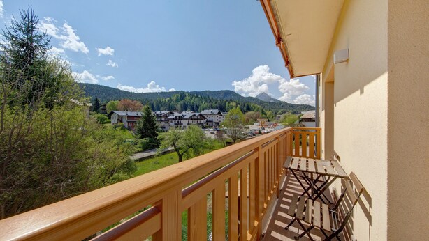 A balcony with a wooden railing overlooking a town, trees, and mountains. - Room 4 – Nene Maria with Terrace and Shared Garden (Pieve di Cadore)