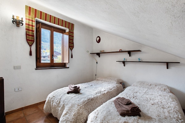 Un dormitorio con dos camas, una ventana con cortinas, un estante en la pared y un enchufe.