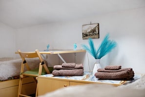 Un dormitorio con cama, un escritorio de madera, una silla, una mesita y un cuadro colgado en la pared.