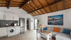 Eine moderne Küche mit Waschmaschine, ein Essbereich mit Tisch und Sofa, und ein Gemälde an der Wand.