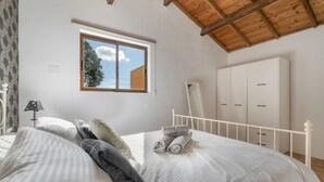 Ein Schlafzimmer mit einem Bett, einem Fenster, einem Kleiderschrank und einer Lampe.