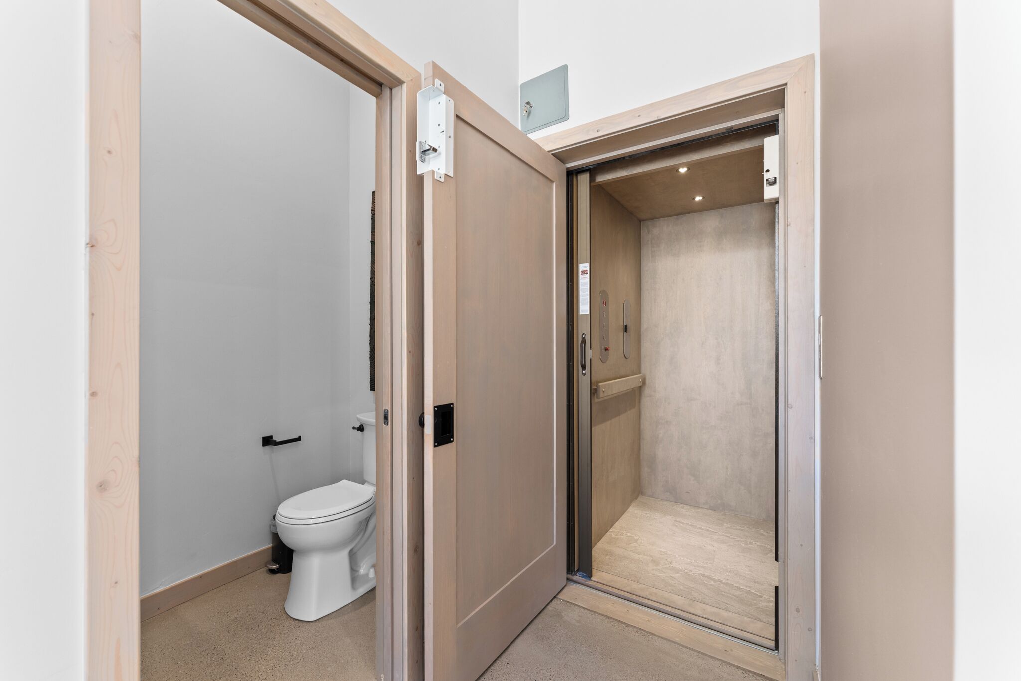 A compact bathroom with a toilet, a shower stall, and a door leading to another room.