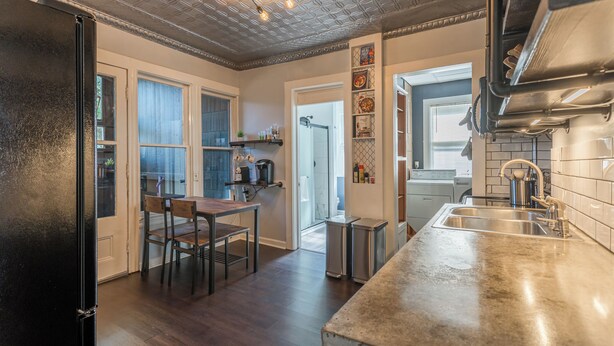 Eine moderne Küche mit einer Edelstahl-Arbeitsplatte, einem Einbauofen und einem Fenster mit Blick auf den Essbereich.