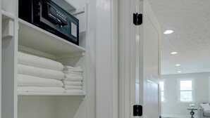 Un vestidor con repisas para toallas dobladas y un electrodoméstico negro.