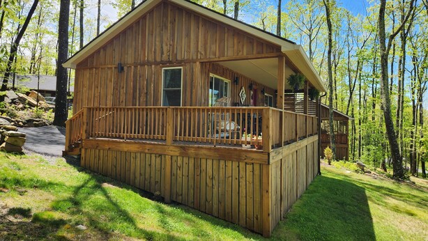 A wooden cabin with a porch, surrounded by trees. - Jungle Boogie in Mountains (Cool Ridge)