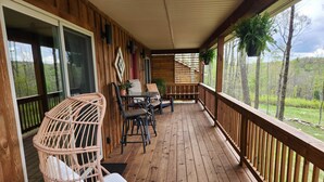 A wooden deck with wicker chairs, a table, and hanging plants. - Jungle Boogie in Mountains (Cool Ridge)