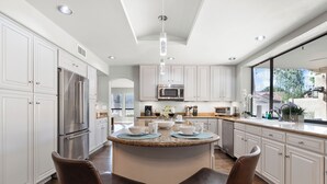 A modern kitchen with white cabinets, stainless steel appliances, and a central island with seating. - Hummingbird Hideaway House with Private Pool in North Scottsdale (Scottsdale)