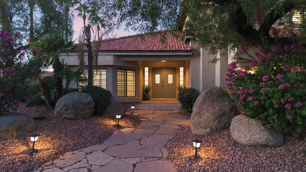 A house with a stone pathway leading to the entrance, large rocks, and flowering plants. - Hummingbird Hideaway House with Private Pool in North Scottsdale (Scottsdale)