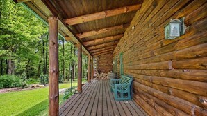Une cabane en rondins avec une terrasse en bois, un banc et une lanterne.