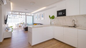 Una cucina moderna con mobili bianchi, un piano di lavoro in marmo e un forno a microonde integrato.