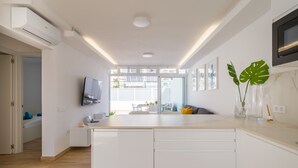 Una cucina moderna con mobili bianchi, forno integrato e televisore a schermo piatto montato a parete.