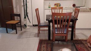 A dining area with a table and chairs, a rug, and a cake on the table. - LOCRI Epizephiri - Apartment 3 pl - Very close to the sea  (Locri)