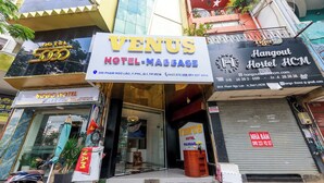 A hotel entrance with a sign for 'Venus Hotel-Massage' and a 'Hangout Hostel HCM' across the street. - Venus Hotel & Massage - Bui Vien Walking (Ho Chi Minh City)