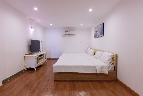 Un dormitorio con una cama, un televisor sobre un mueble bajo y un equipo de aire acondicionado en la pared.